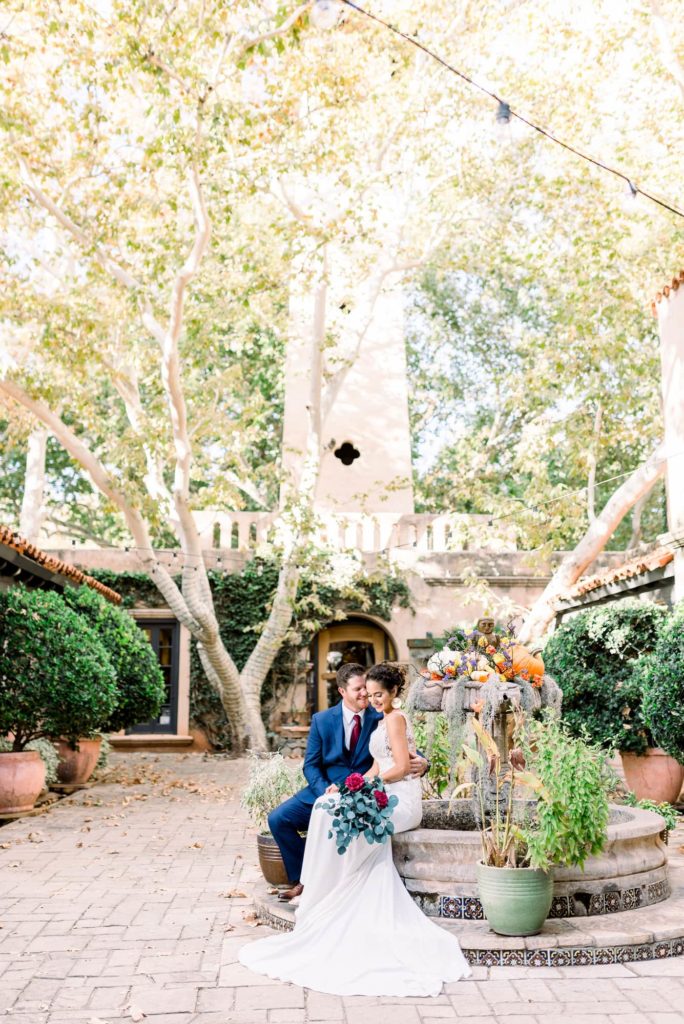 Couple sitting in front of the bell tower at Tlaquepaque on the fountain.