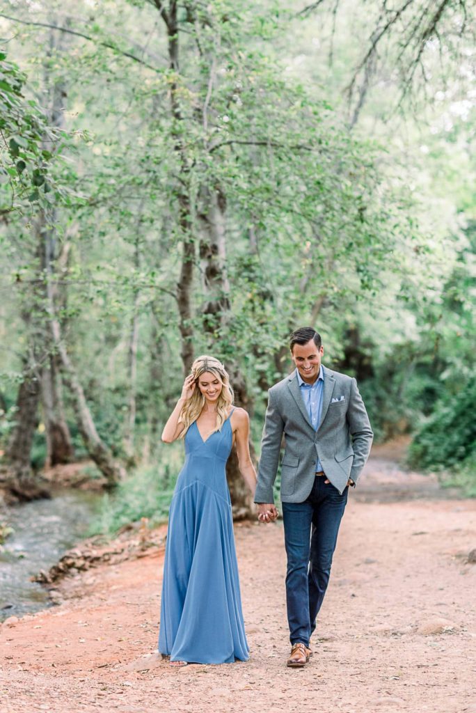 Couple walking holding hands along a path by a creek in Sedona.