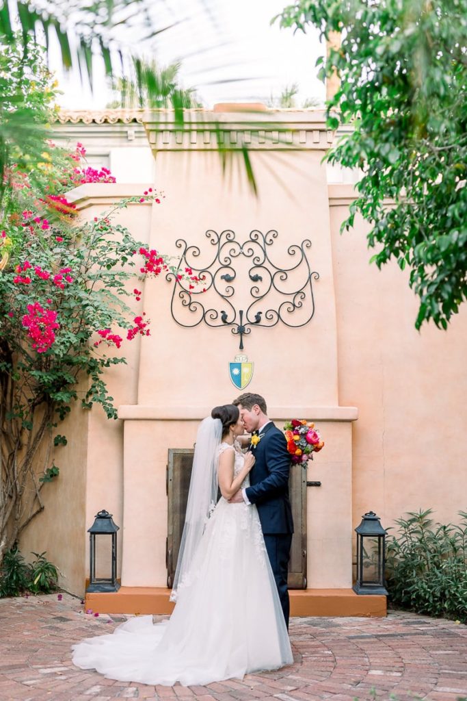 Groom kissing bride outside showing the beautiful buildings of the Royal Palms