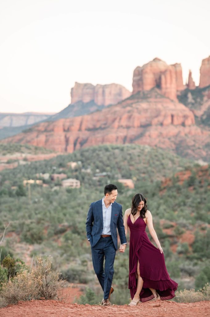 Couple walking with mountain views during engagement in Sedona