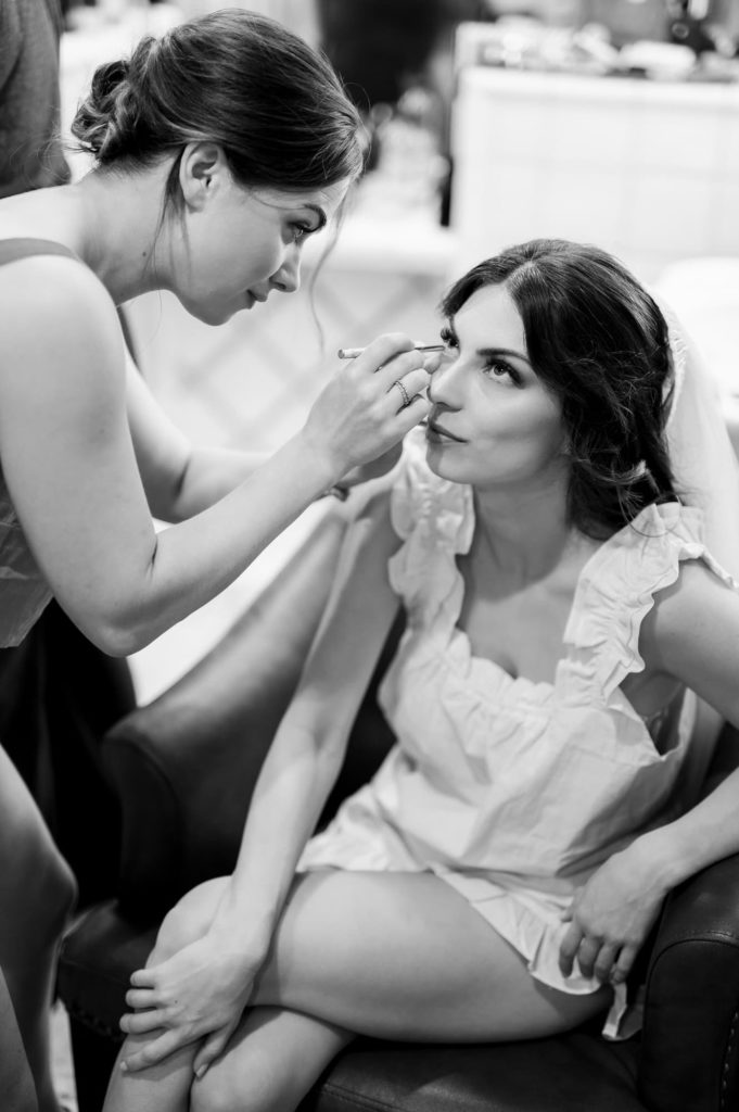 Bride putting eye liner on in black and white