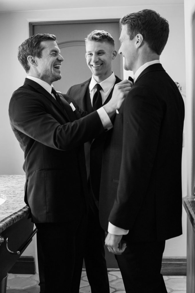 Best man straightening the grooms bow tie