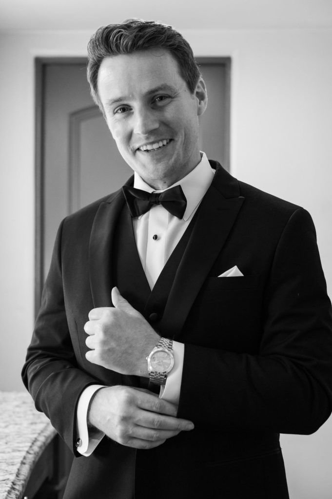 Groom looking at camera smiling showing watch and cuff links