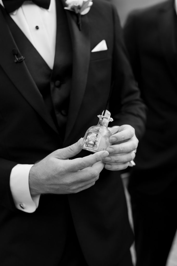 Groom holing a small bottle of bourbon