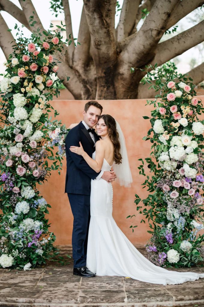 Bride and groom portrait at the alter surrounded by flowers