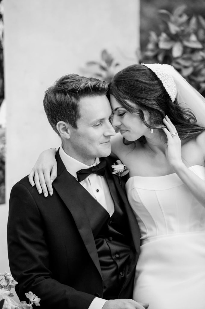 Bride sitting on Grooms lap touching foreheads smiling