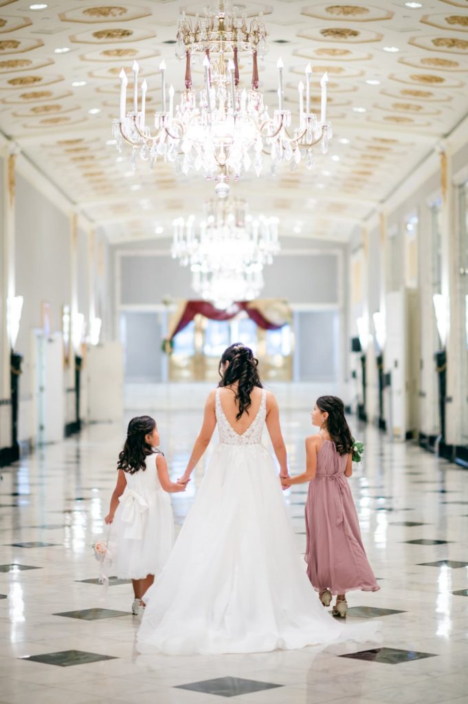 Bride walking down the grand Hallway holding her two daughters hands at the Mayflower Hotel DC Wedding venue.