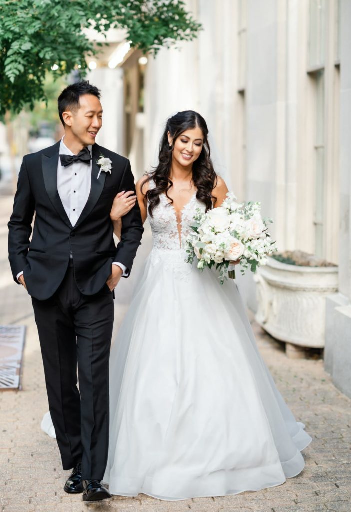 Groom walking down the sidewalk with Bride holding his arm in Washington DC