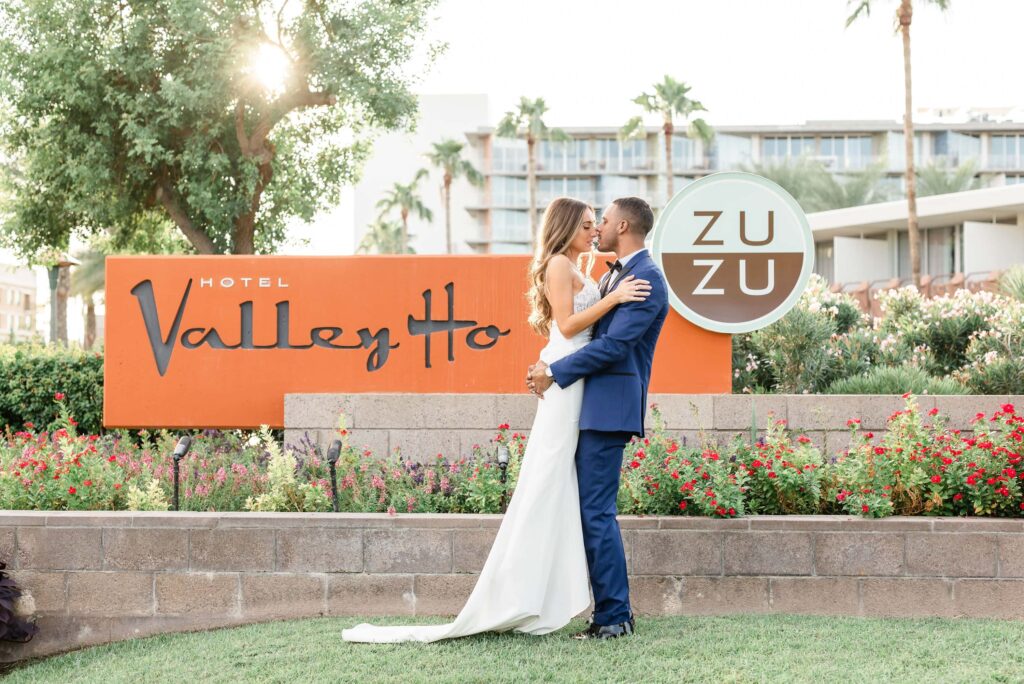 Groom lifting bride and kissing her in front of the Hotel Valley Ho sign.